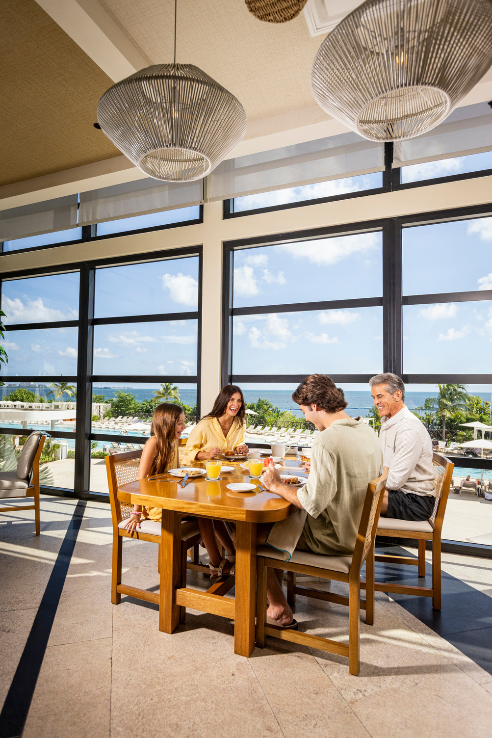 Family dining at a restaurant with ocean views, large windows, and modern lighting in a Cancun all-inclusive resort.