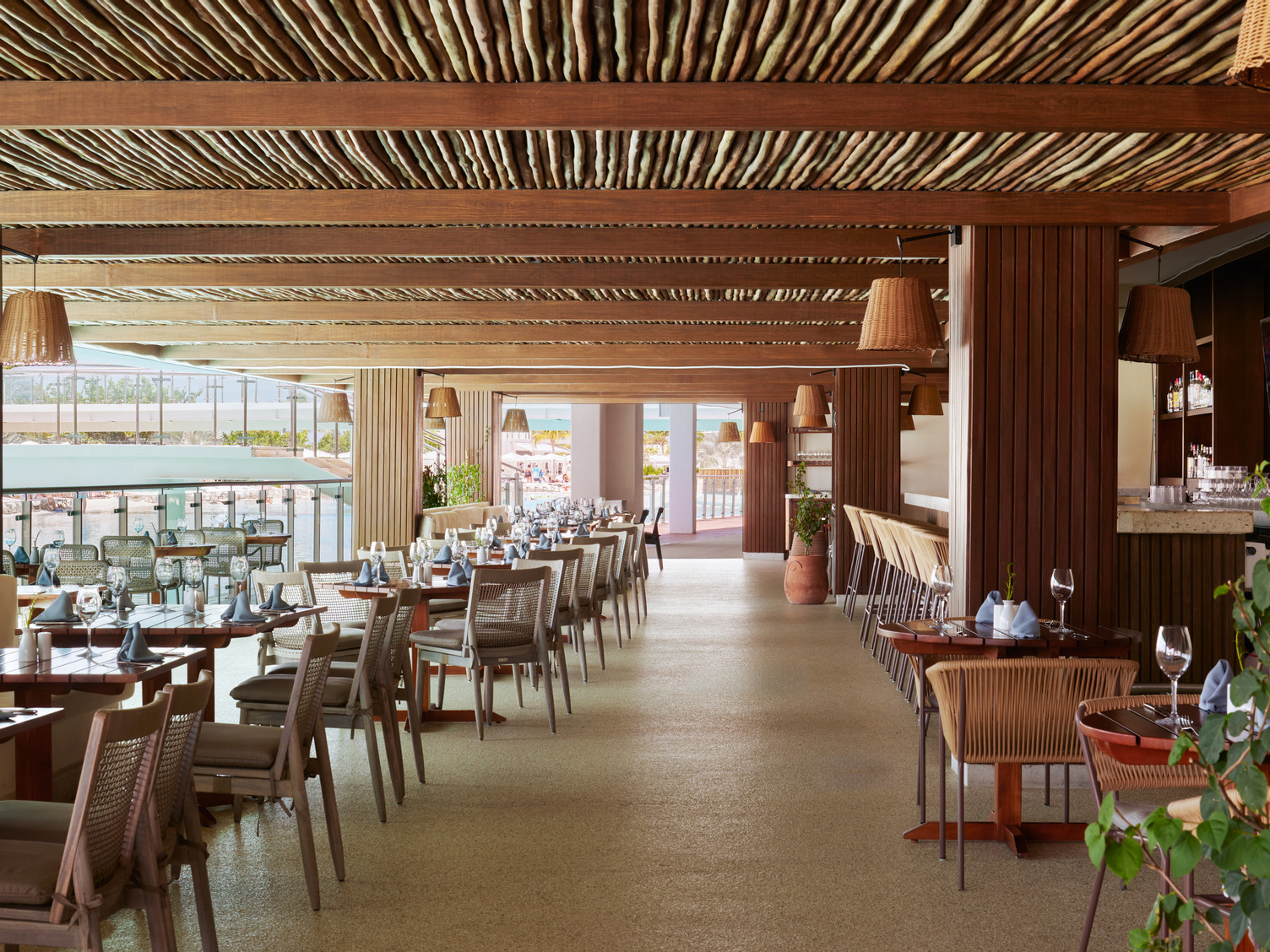 AVA Bayside Cafe in Cancun with wooden decor, neatly arranged tables, and chairs under a rustic ceiling.