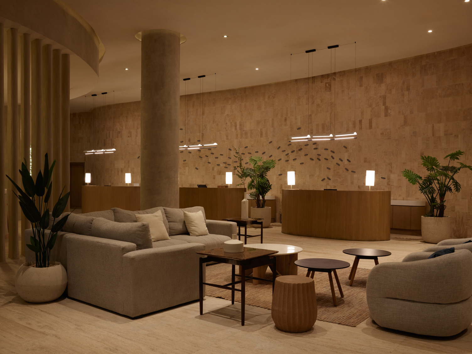 Elegant spa lobby with neutral tones, modern furnishings, and soft lighting. Cozy seating and tables enhance tranquility.
