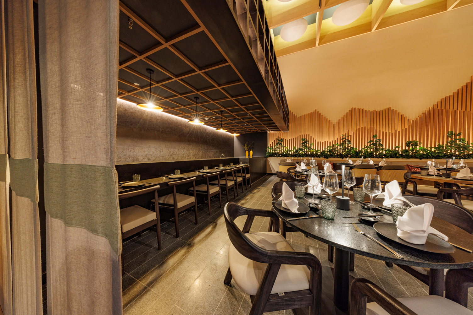 Elegant indoor dining area with set tables, neatly folded napkins, wooden decor, and ambient lighting at UNICO 20°105°.