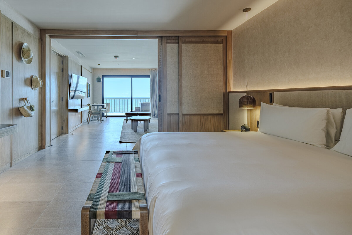 Ocean-view guest room at UNICO 20°105°, bright bedroom with white bed, woven decor, and a terrace overlooking the sea.