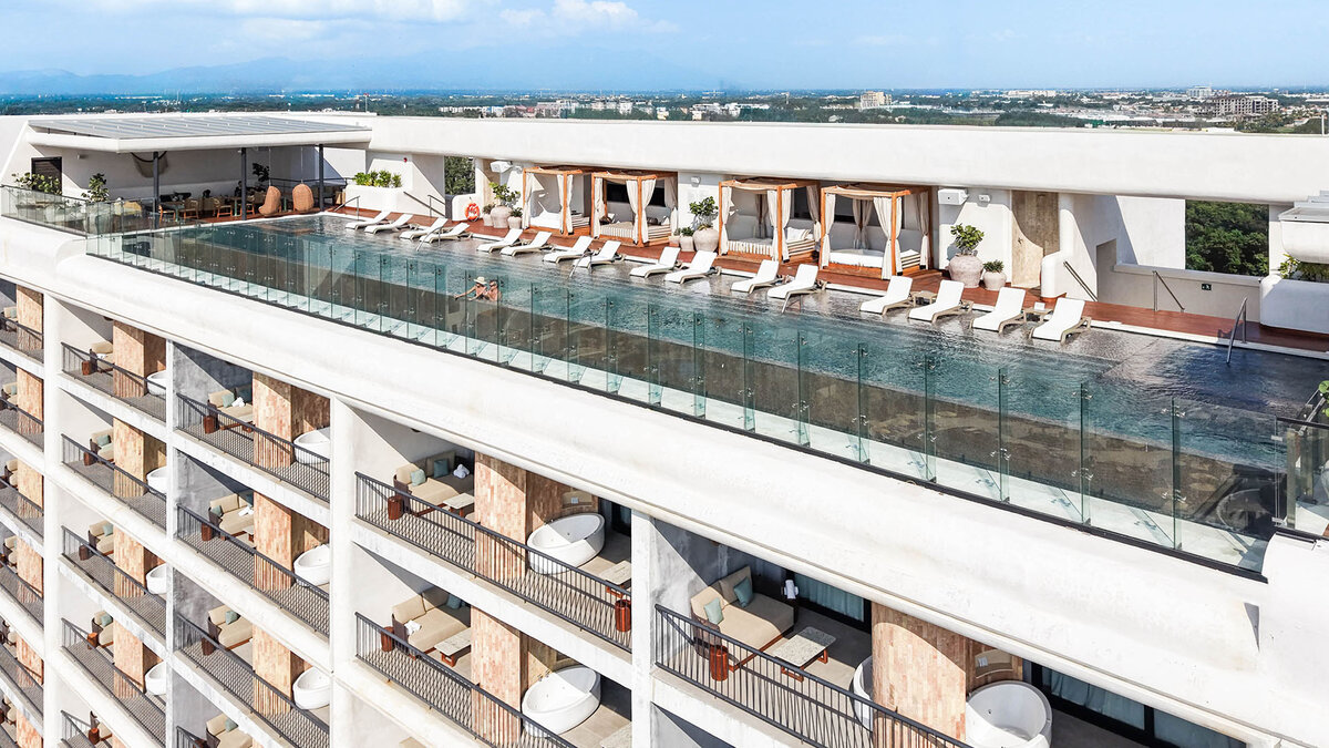 Rooftop pool deck at UNICO 20°105° with lounge chairs, cabanas, and expansive views of the Pacific Ocean and coastline.