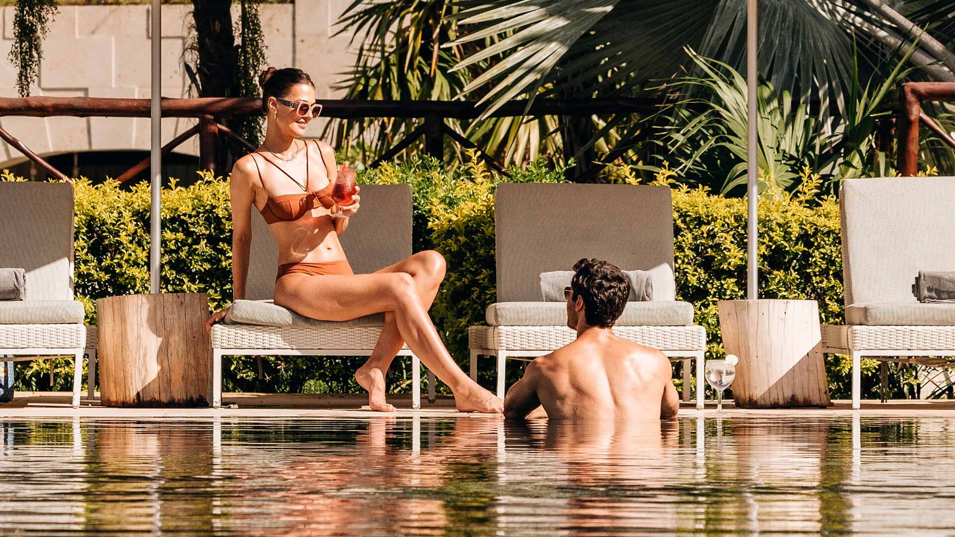 Guests relaxing poolside at UNICO 20°105° Riviera Nayarit, enjoying drinks under the sun.