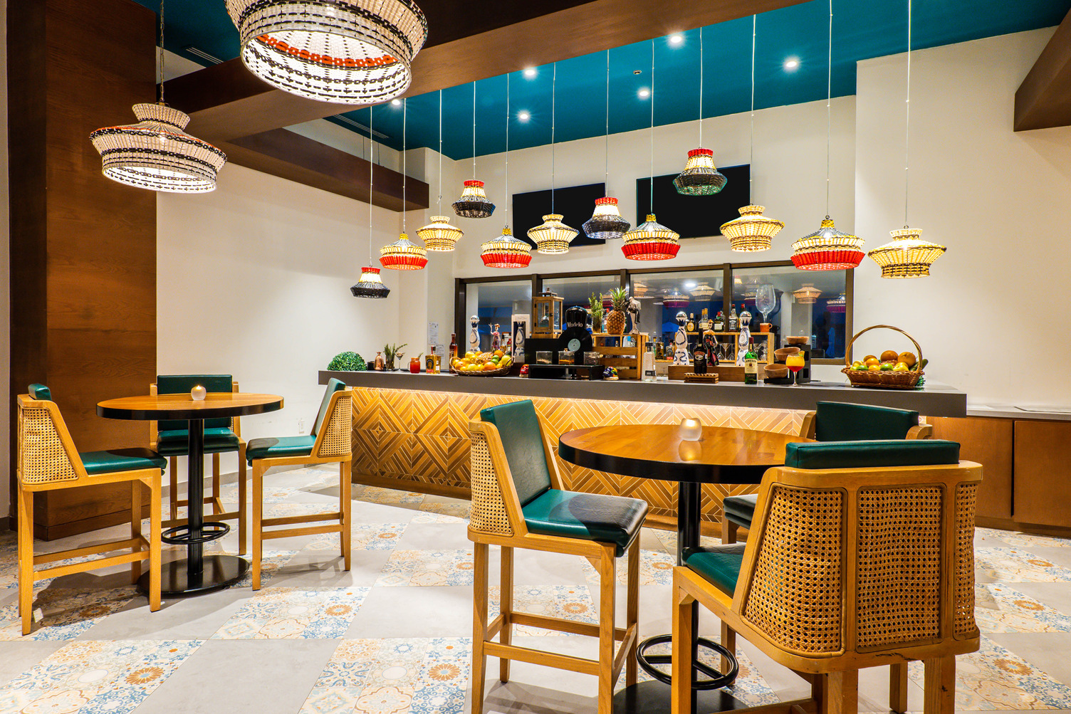 Vibrant restaurant interior with wooden tables, wicker chairs, and colorful hanging lamps in Cabo San Lucas.