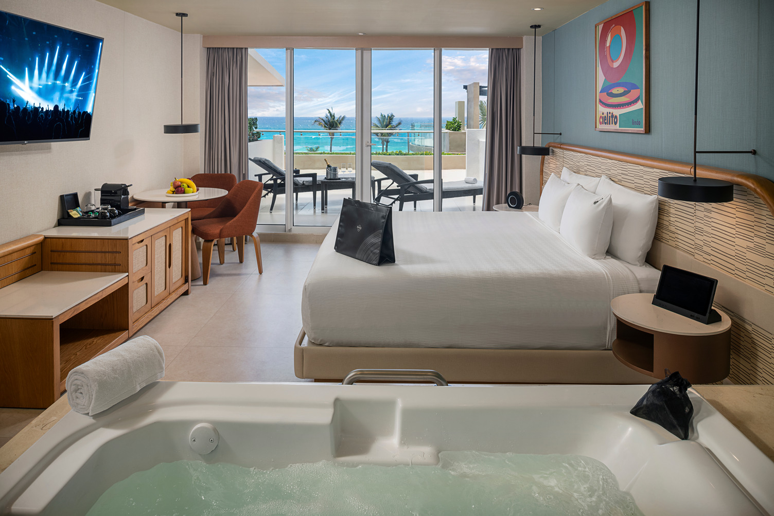 Lujosa habitación de hotel con cama king, vista al océano, jacuzzi, balcón, bebidas y arte en las paredes en Hard Rock Cancun