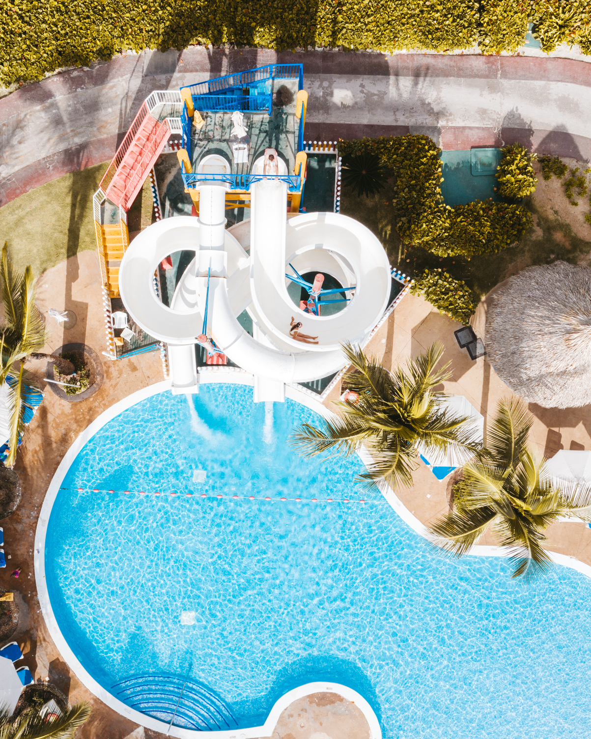 Vista aérea del área de albercas para niños en Hard Rock Punta Cana con toboganes y palmeras.