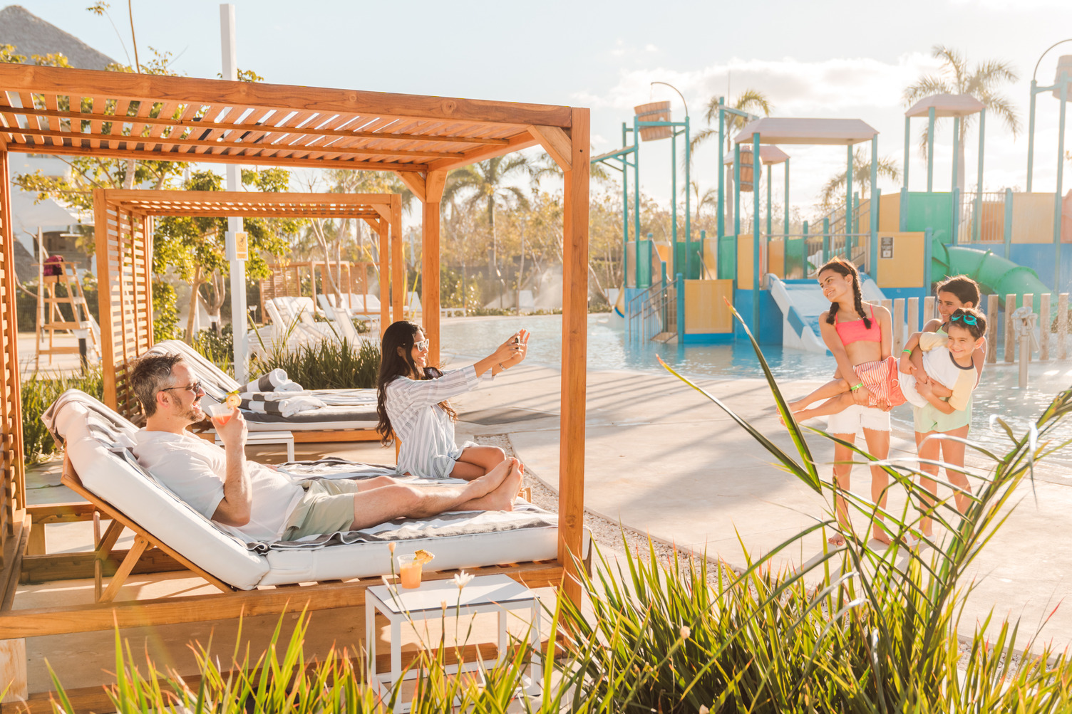 Guests enjoy cabanas and waterslides at an all-inclusive resort pool in Punta Cana under sunny skies.