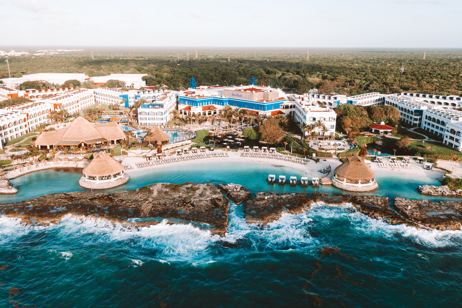 Vista aérea del Hard Rock Hotel Riviera Maya, mostrando albercas, cabañas y frente al océano en un entorno tropical exuberant