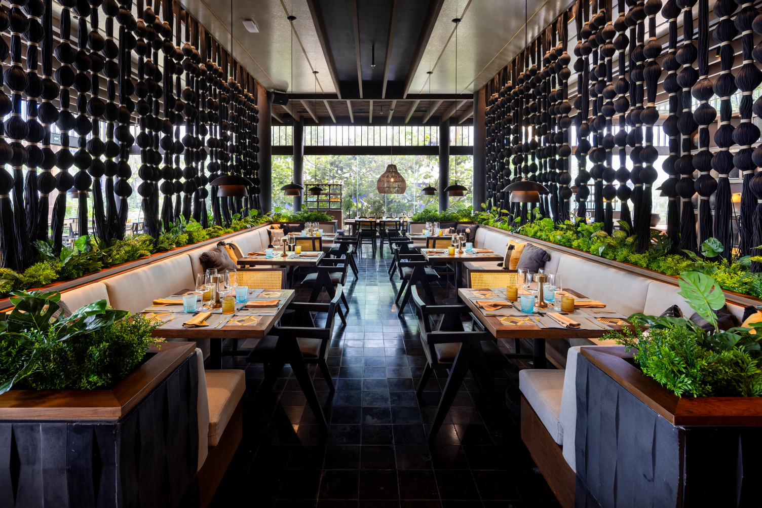 Interior de restaurante de lujo con exuberante vegetación, decoración de madera y elegantes mesas en Hard Rock Riviera Maya.