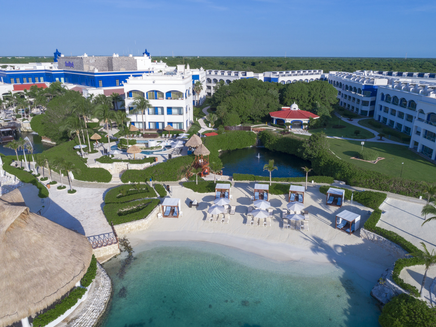 Vista aérea de Heaven en Hard Rock Riviera Maya, mostrando albercas, tumbonas, área de playa y exuberante paisaje verde.