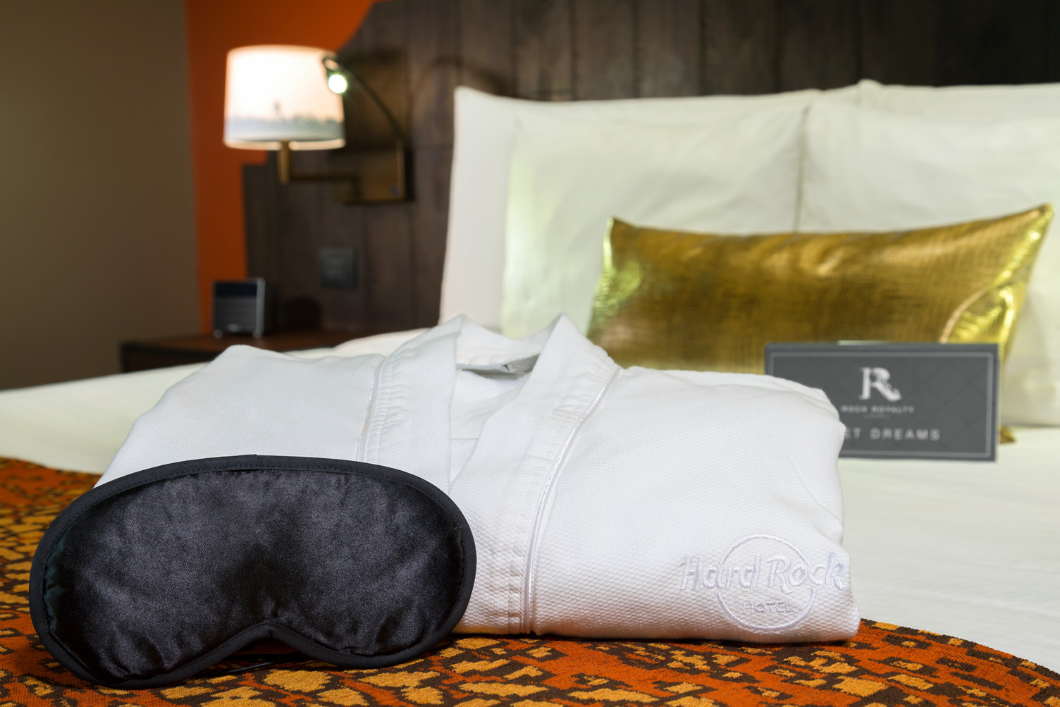 Luxury hotel room with a bathrobe, eye mask on bed, elegant decor, and nighttime ambiance.