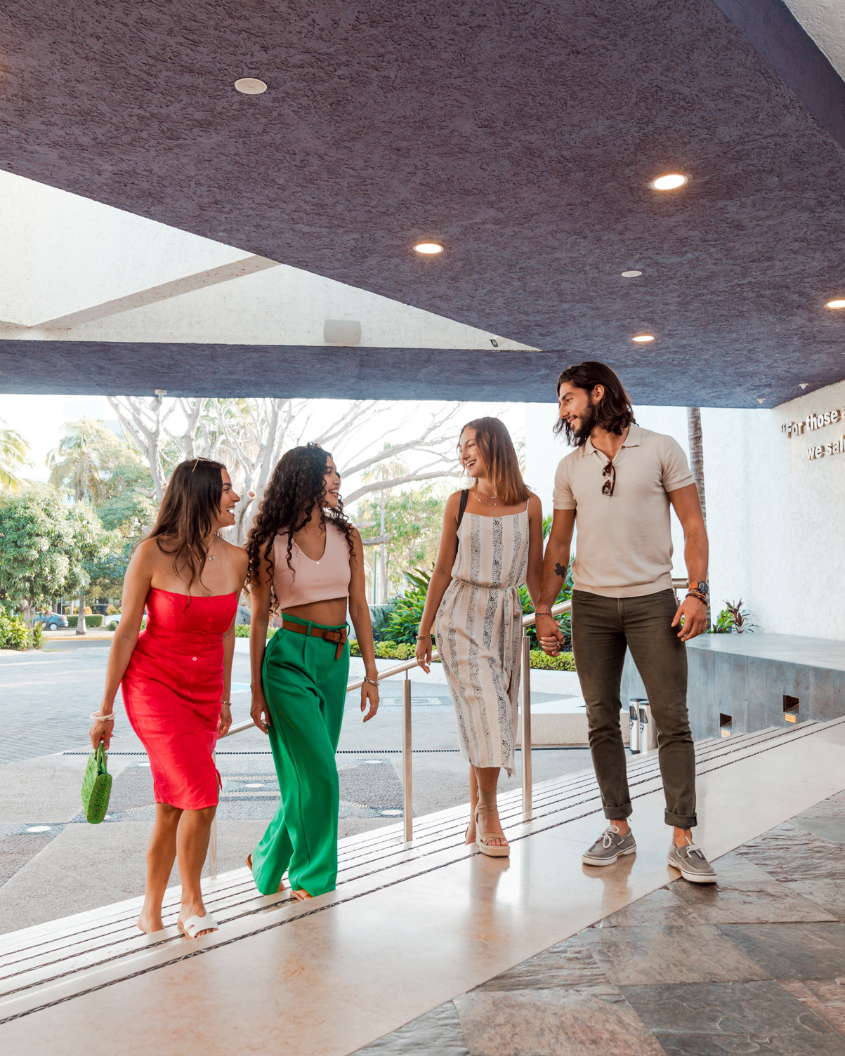 Four people walking together under a covered entrance at a hotel, smiling and talking.