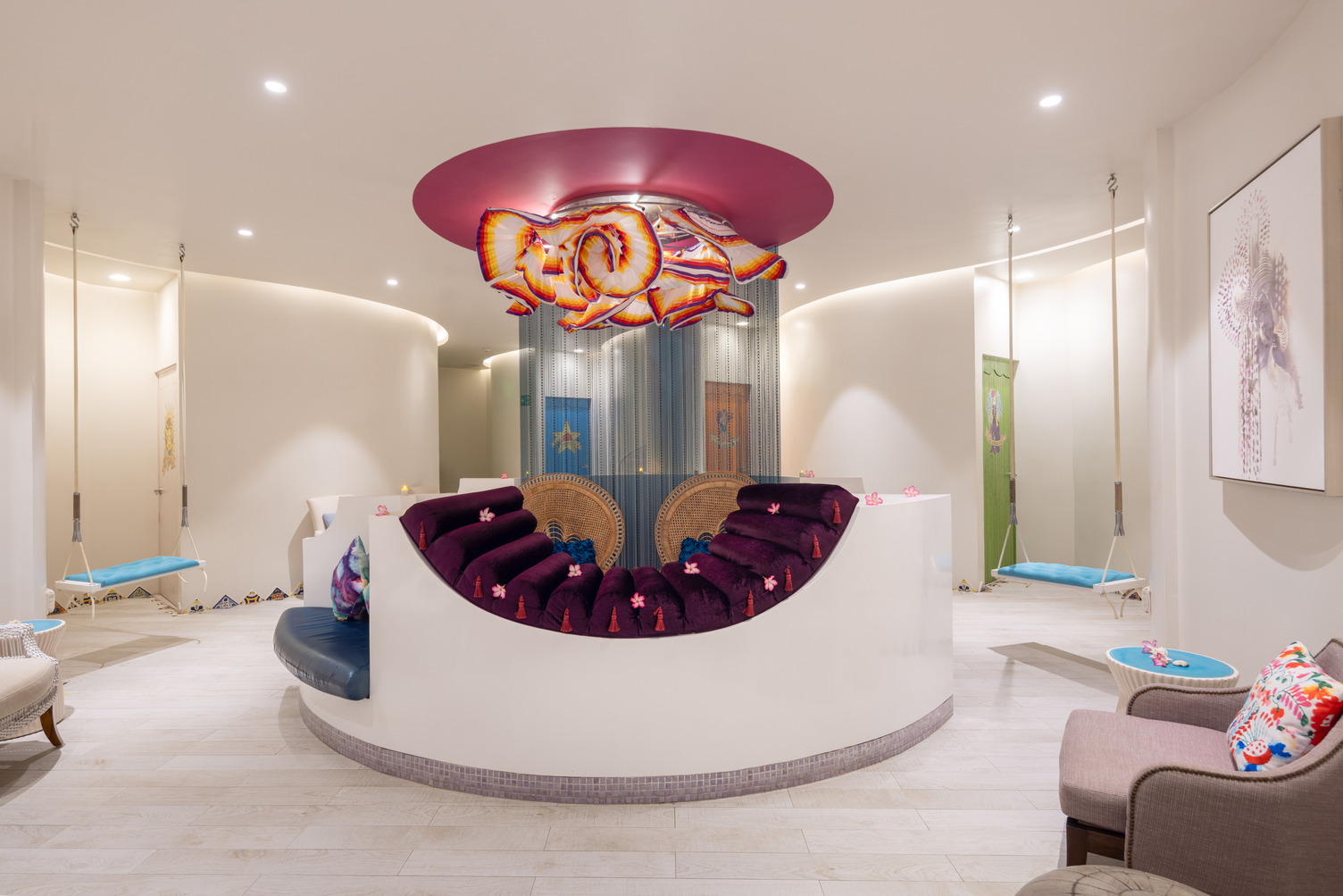 Colorful spa lounge with plush seating, vibrant ceiling art, and swings at an upscale resort in Puerto Vallarta.