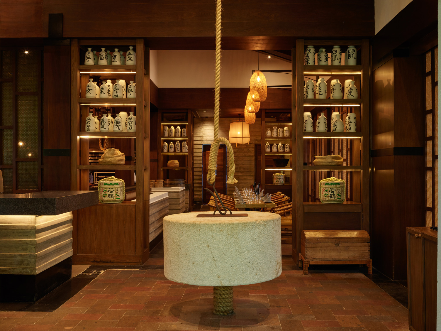 Interior elegante de restaurante con molino de piedra como pieza central, estanterías de madera, jarras de cerámica e ilumina